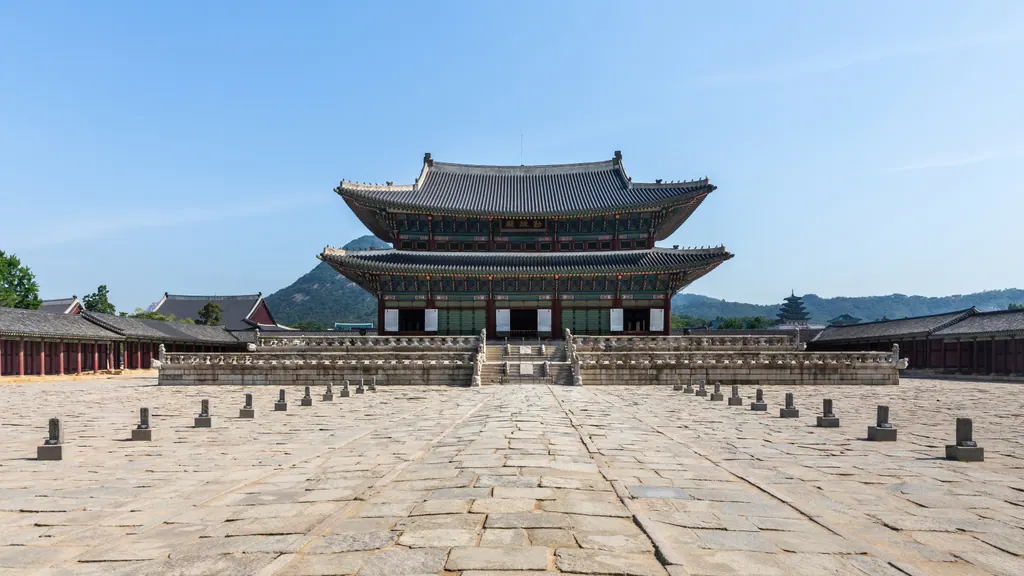 Geunjeongjeon throne hall at Gyeongbokgung Palace in Seoul, seen across its stone courtyard under a blue sky