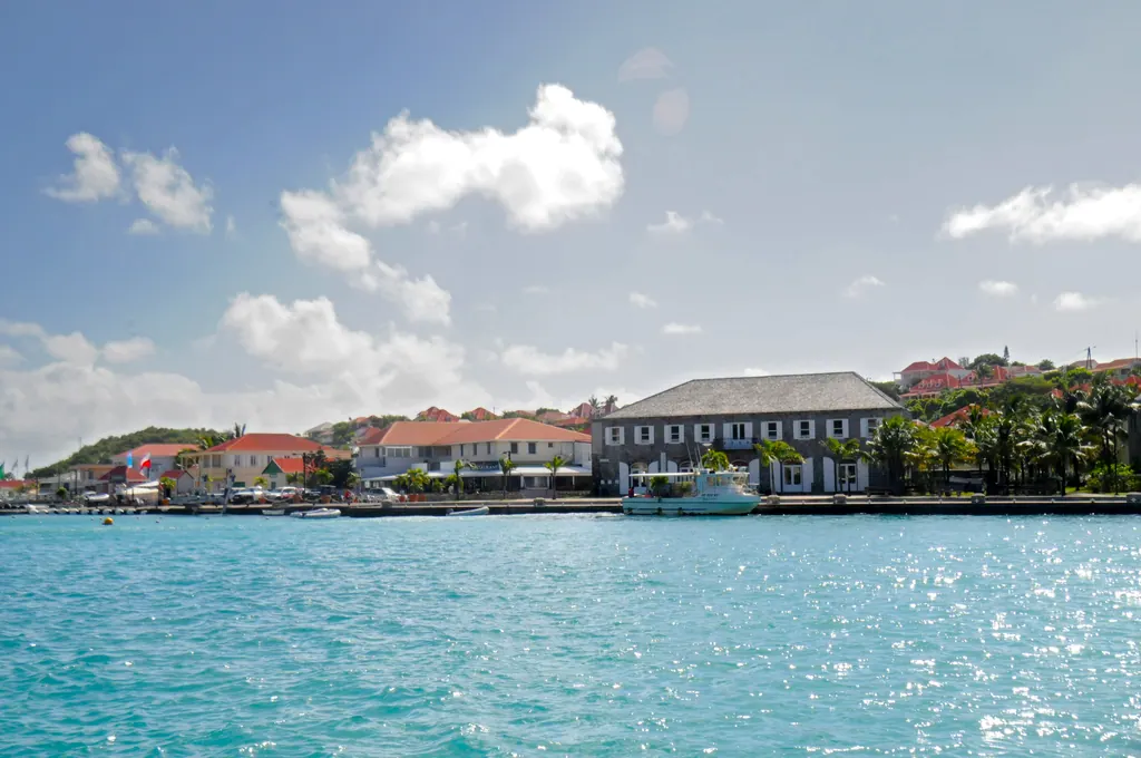 Gustavia harbor on Saint Barts seen from the water, with red roofed buildings and turquoise sea