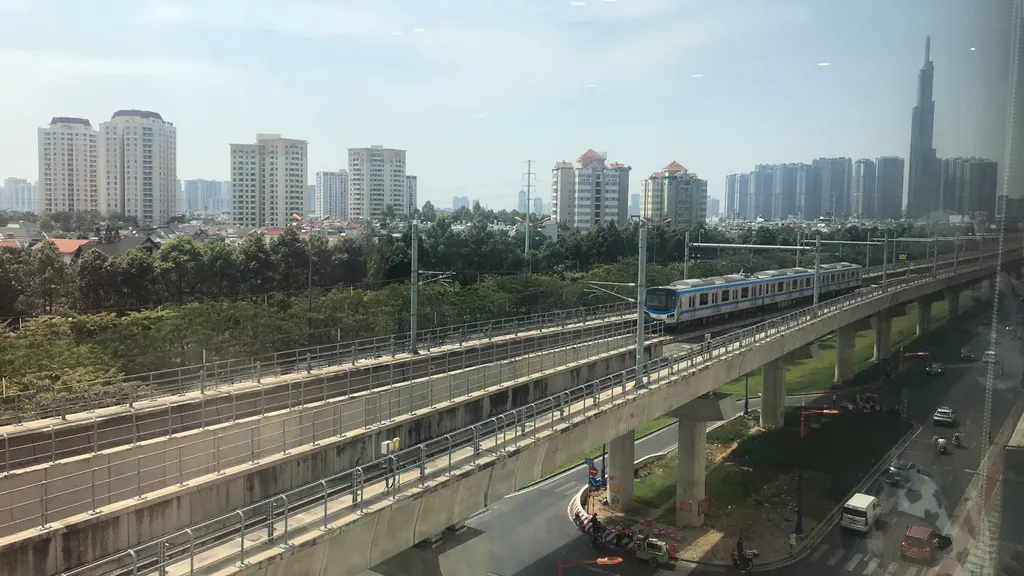 An elevated Metro Line 1 train crosses Thao Dien on a viaduct with Ho Chi Minh City's skyline behind it