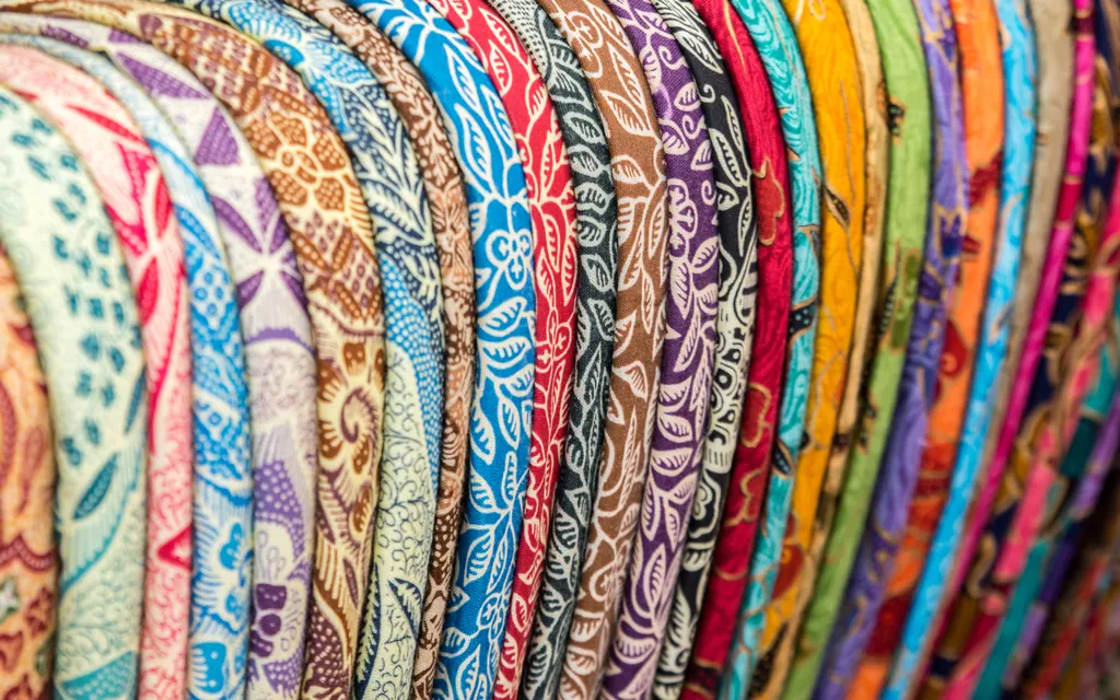 Rows of colorful batik fabrics hanging side by side at the Ubud Art Market in Bali