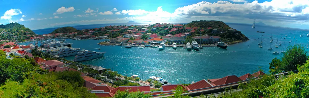 Panoramic view of Gustavia harbor on St. Barts with red roofs, yachts and turquoise water