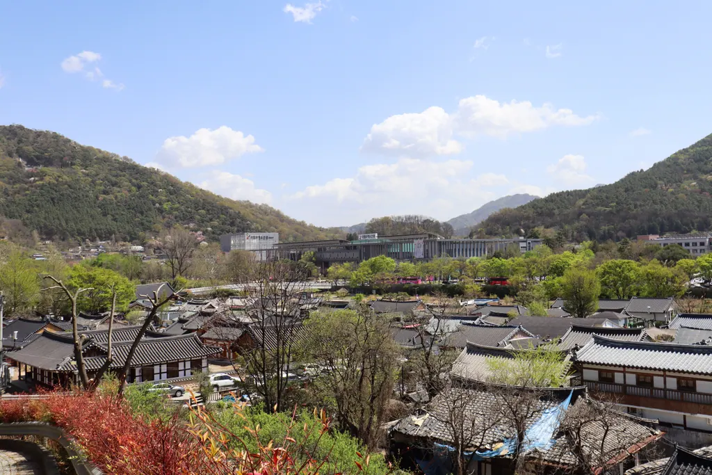 Tiled roofs of Jeonju Hanok Village with green hills and blue sky behind