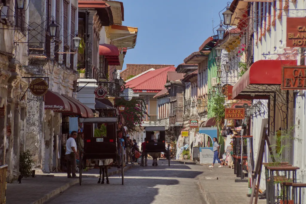 Calle Crisologo in Vigan, a cobblestone street lined with Spanish colonial houses, shop fronts and a horse-drawn calesa