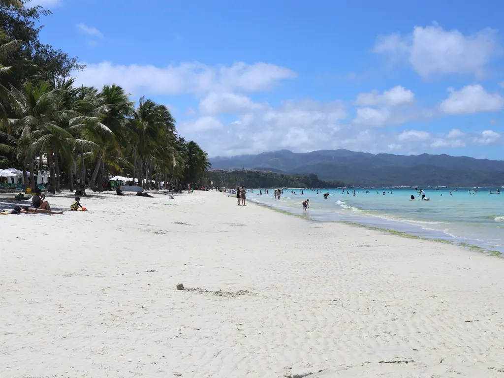 White Beach on Boracay on a sunny day, with palm trees, white sand and turquoise water