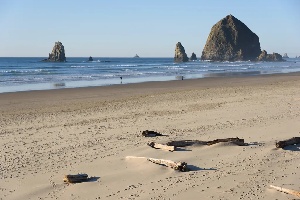 Haystack Rock and smaller sea stacks rising from the surf at Cannon Beach on a clear day