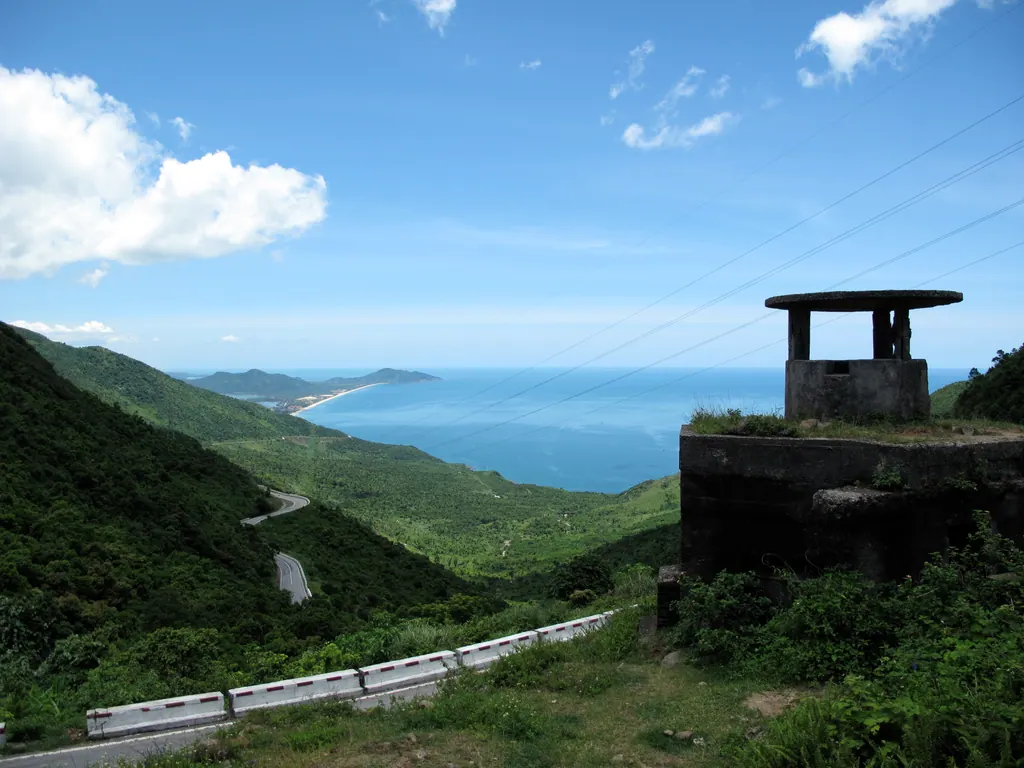 The coast road and green hills seen from the Hai Van Pass, with a bay and a sandy beach in the distance