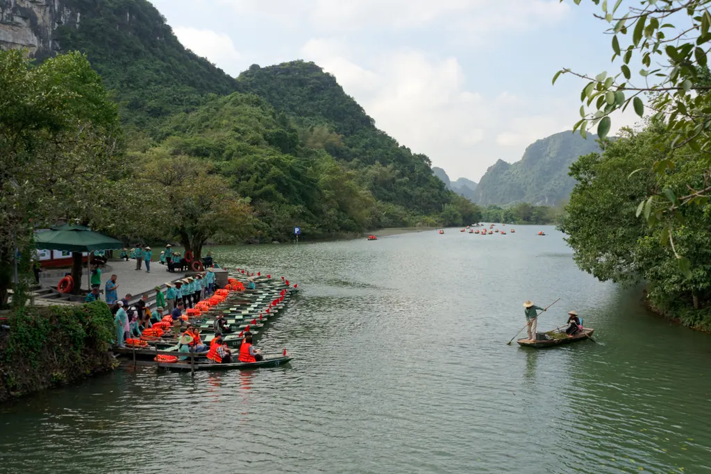 Rowing boats waiting by the river below limestone hills at Trang An in Ninh Binh