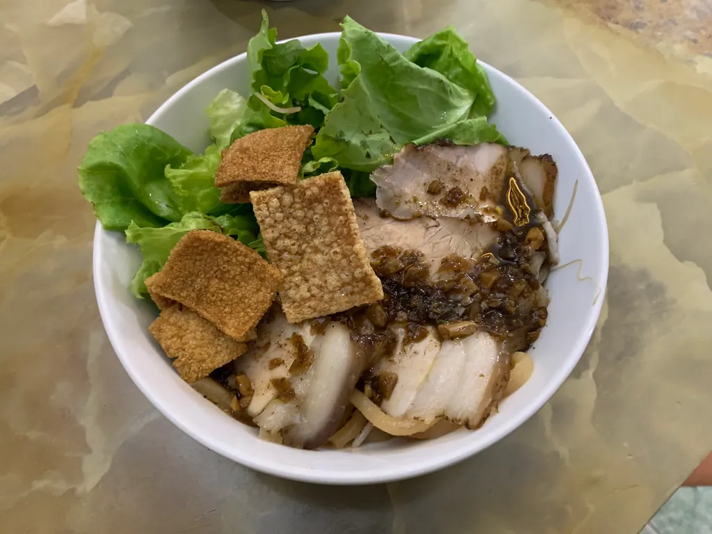 A bowl of cao lau in Hoi An with sliced pork, lettuce and crispy rice crackers
