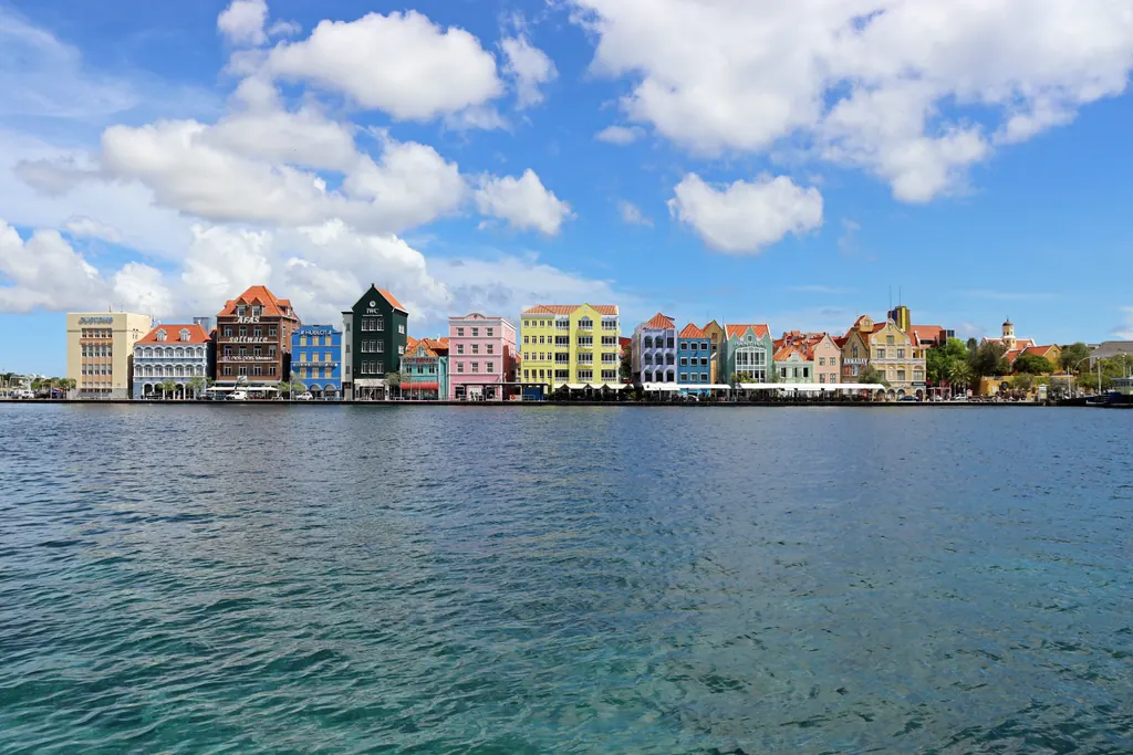 Colorful colonial buildings along the Handelskade waterfront in Willemstad, Curaçao, under a blue sky