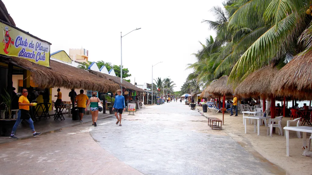 The beachfront walkway in Mahahual lined with palm trees and thatched restaurants